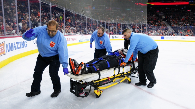 Referee Mitch Dunning, center, is stretchered off the ice after an injury during the first period of an NHL hockey game between the Philadelphia Flyers and the Colorado Avalanche, Monday, Nov. 18, 2024, in Philadelphia. (AP Photo/Derik Hamilton)