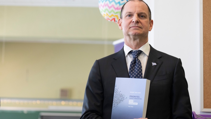 Quebec Finance Minister Eric Girard, holds a copy of his 2024 budget during a press conference in Longueuil, Que., Monday, March 11, 2024. (Christinne Muschi / The Canadian Press)