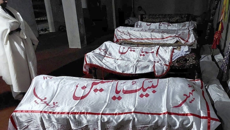 A mourner stands beside the bodies of the victims. who were killed in a gunmen firing incident, before their funeral prayer, in Parachinar, main town of Kurram district of Pakistan's northwestern Khyber Pakhtunkhwa province, Friday, Nov. 22, 2024. (AP Photo/Hussain Ali)