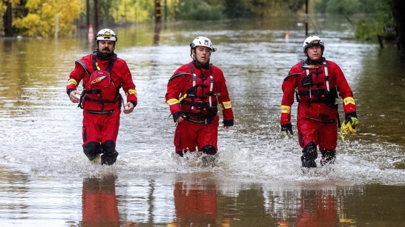 Firefighters walk through floodwaters while responding to a rescue call in unincorporated Sonoma County, Calif., on Friday, Nov. 22, 2024. (AP Photo/Noah Berger)