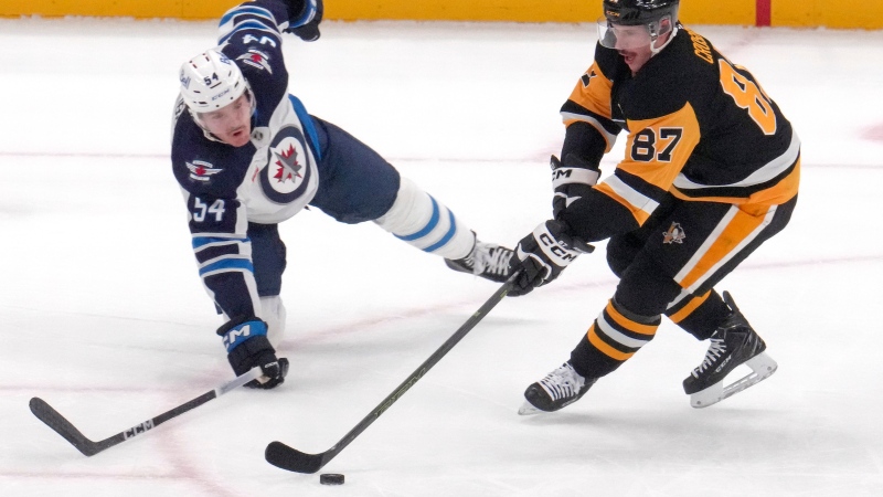 Pittsburgh Penguins' Sidney Crosby (87) is defended by Winnipeg Jets' Dylan Samberg (54) during the first period of an NHL hockey game Friday, Nov. 22, 2024, in Pittsburgh. (AP Photo/Gene J. Puskar)