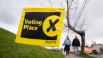 A sign directing voters in the Nova Scotia provincial election is seen as pedestrians walk past in Halifax, Tuesday, Nov. 26, 2024. (THE CANADIAN PRESS/Darren Calabrese)