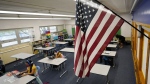  An American flag hangs in a classroom as students work on laptops in Newlon Elementary School, Aug. 25, 2020, in Denver. (AP Photo/David Zalubowski, File)