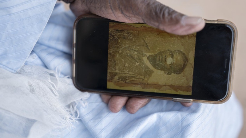 Biram Senghor, whose father was killed in 1944, holds a phone with a photo of his father, in Rufisque, Senegal, Thursday, Nov. 28, 2024. (AP Photo/Sylvain Cherkaoui)
