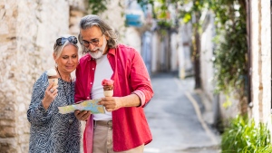 Mature couple reviewing  a map while eating ice cream and touring an old village. (iStock)