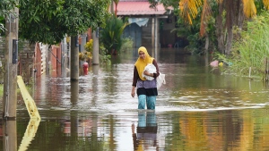 A woman wades through floodwater in Tumpat, on the outskirts of Kota Bahru in Kelantan state on the east coast of Malaysia, Tuesday, Dec. 3, 2024. (AP Photo/Vincent Thian) 