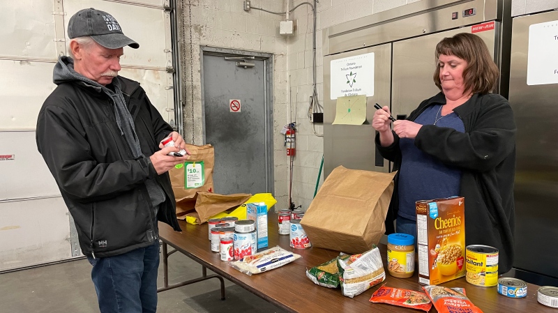 Society of St. Vincent de Paul volunteers Dave Leslie and Jennifer Wilson sort food donations in Windsor, Ont., on Wednesday, Dec. 4, 2024. (Michelle Maluske/CTV Windsor)