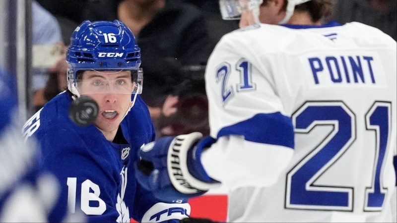 Toronto Maple Leafs right wing Mitch Marner (16) keeps his eye on the puck as Tampa Bay Lightning centre Brayden Point (21) looks on during first period NHL hockey action in Toronto, Monday, Oct. 21, 2024. THE CANADIAN PRESS/Frank Gunn