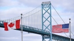 Canadian and American flags fly near the Ambassador Bridge at the Canada-USA border crossing in Windsor, Ont. on March 21, 2020.  (THE CANADIAN PRESS/Rob Gurdebeke)