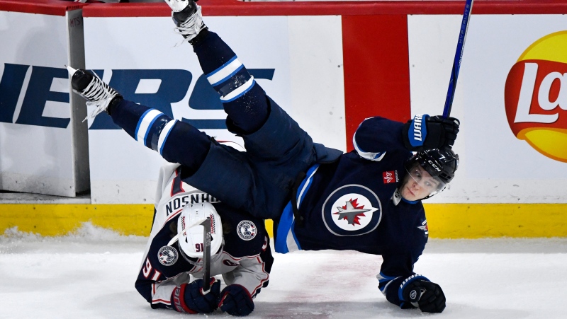 Columbus Blue Jackets' Kent Johnson (91) trips up Winnipeg Jets' Vladislav Namestnikov (7) during third period NHL hockey action in Winnipeg, Sunday, Dec. 8, 2024. (Fred Greenslade/The Canadian Press)