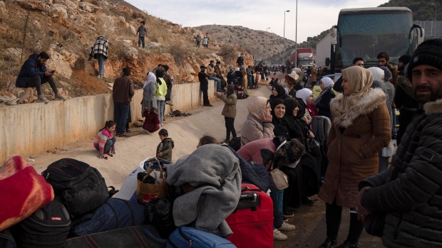 Syrians wait on the road to cross into Lebanon near the Masnaa crossing border, as seen from east Lebanon, Wednesday, Dec. 11, 2024. (AP Photo/Leo Correa)