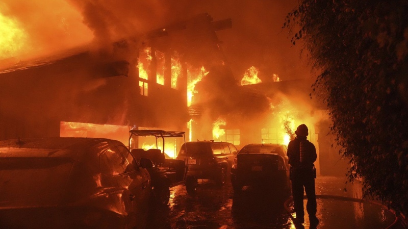 A firefighter sprays water on a home as it burns in the Franklin Fire in Malibu, Calif., Tuesday, Dec. 10, 2024. (AP Photo/Jae C. Hong)
