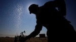 In this file photo, an oil worker adjusts a valve releasing a spray of water while working on oil pipelines Thursday, Feb. 18, 2016, in the desert oil fields of Sakhir, Bahrain. (AP Photo/Hasan Jamali)