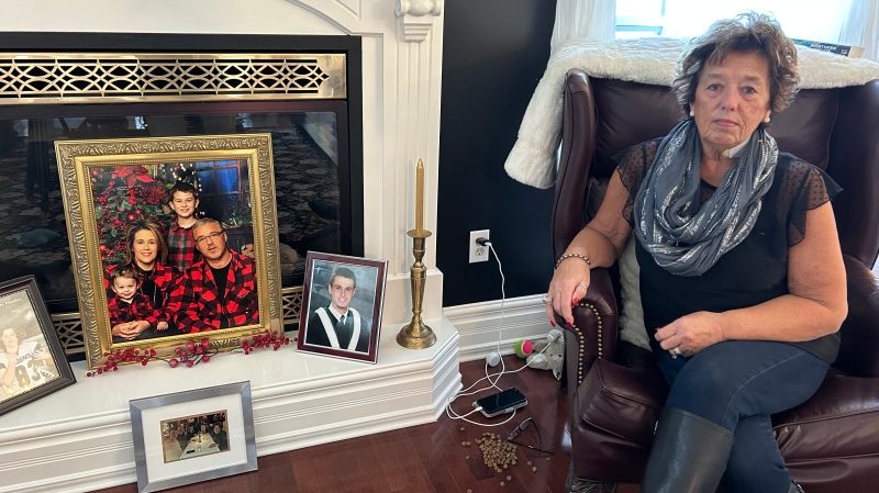 David’s mother, Cathy Mitchell Cooper, is pictured beside a picture of her son and his family. (CTV/Avery MacRae)