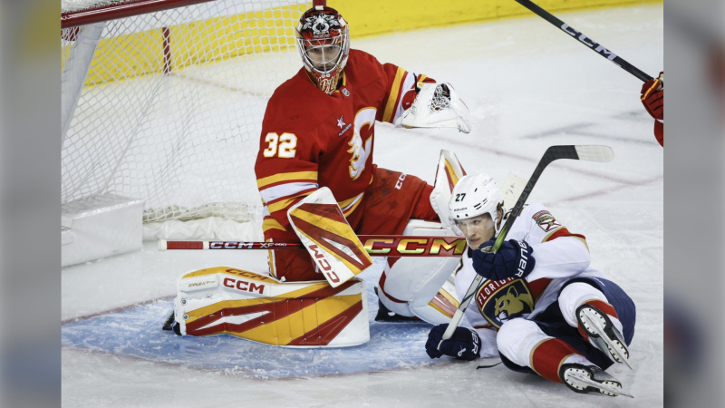 Florida Panthers' Eetu Luostarinen, right, crashes into Calgary Flames goalie Dustin Wolf during second period NHL hockey action in Calgary, Alta., Saturday, Dec. 14, 2024. THE CANADIAN PRESS/Jeff McIntosh