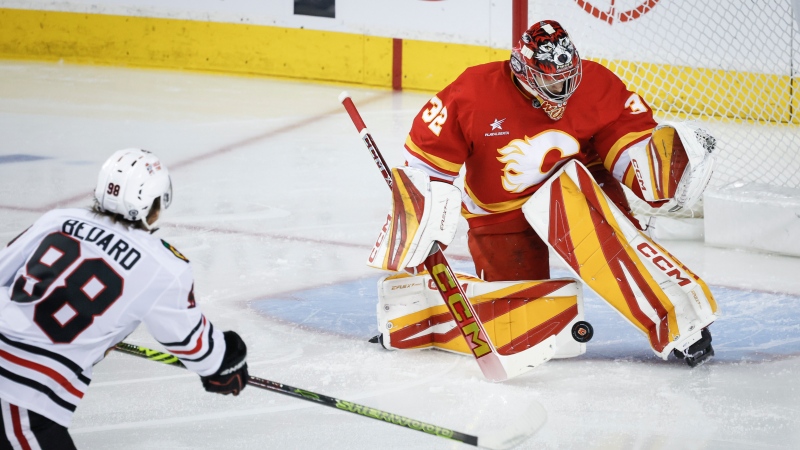 Chicago Blackhawks' Connor Bedard, left, has his shot stopped Calgary Flames goalie Dustin Wolf during first period NHL hockey action in Calgary, Alta., Saturday, Dec. 21, 2024. (Jeff McIntosh)