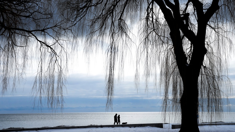 People walk on the snowy beach along Lake Ontario in Toronto on Tuesday, February 8, 2022. THE CANADIAN PRESS/Nathan Denette