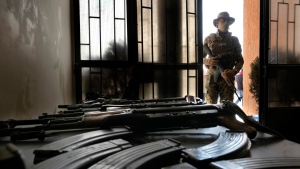 A Syrian fighter stands guard next to AK-47 rifles surrendered by members of ousted Syrian President Bashar Assad's army and pro-government militias in Damascus, Syria, Monday, Dec. 23, 2024. (AP Photo/Hussein Malla)