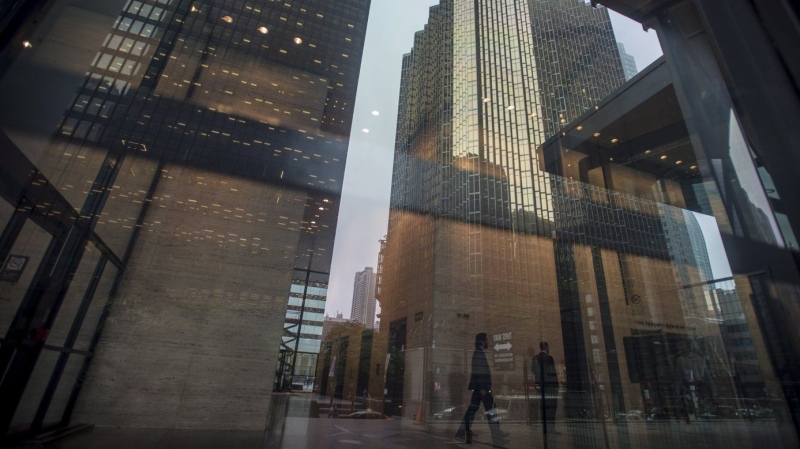 The financial district is reflected on the window as business people make their way through the Toronto Dominion Centre in Toronto, Wednesday, June 27, 2018. THE CANADIAN PRESS/Tijana Martin