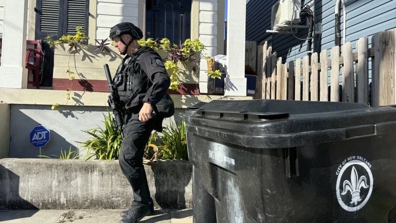 A New Orleans police officer searches the area near a crime scene after a vehicle drove into a crowd on Canal and Bourbon Street earlier, Wednesday Jan. 1, 2025. (AP Photo/Jack Brook)