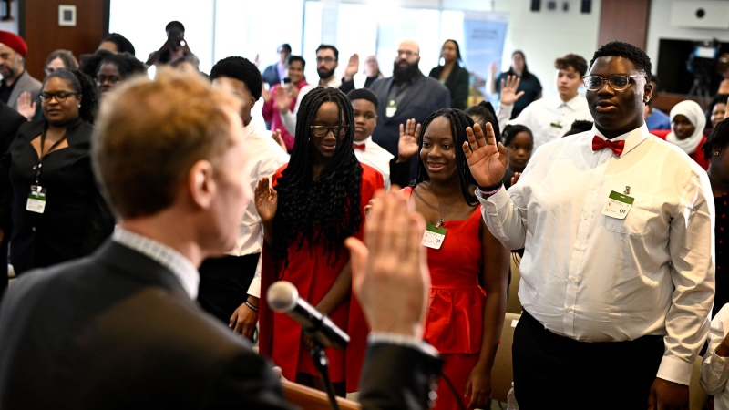 New Canadians raise their right hands as Minister of Immigration, Refugees and Citizenship Marc Miller, left, administers the Oath of Citizenship, during a citizenship ceremony in Ottawa, on Wednesday, Feb. 28, 2024. THE CANADIAN PRESS/Justin Tang