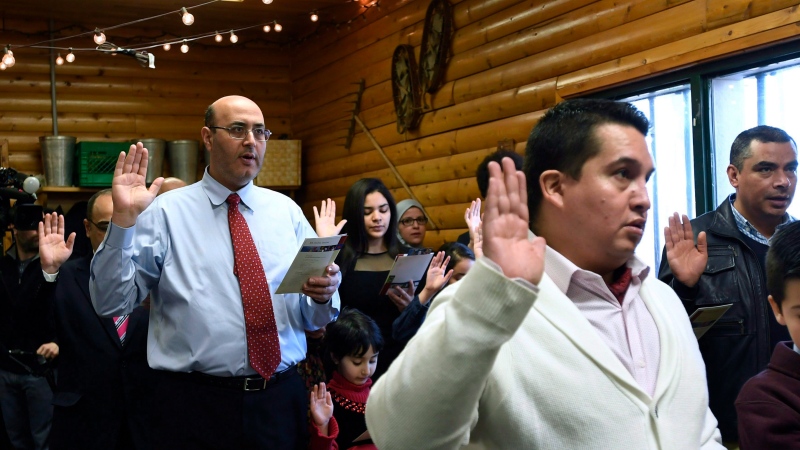 Joseph Sarraf, left, raises his hand as he swears the oath of Canadian Citizenship along with 19 others during a citizenship ceremony at the Vanier Sugar Shack in Ottawa on Wednesday, April 11, 2018. THE CANADIAN PRESS/Justin Tang