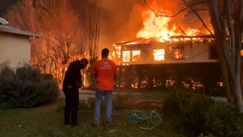 Volunteers try to douse Gail's home and yard to keep the flames at bay. (CNN via CNN Newsource)
