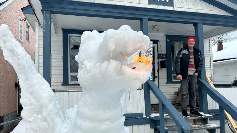 Leigh Keast poses with his ice dragon sculpture outside of his Winnipeg home on January 9, 2025. (Scott Andersson/CTV News Winnipeg)