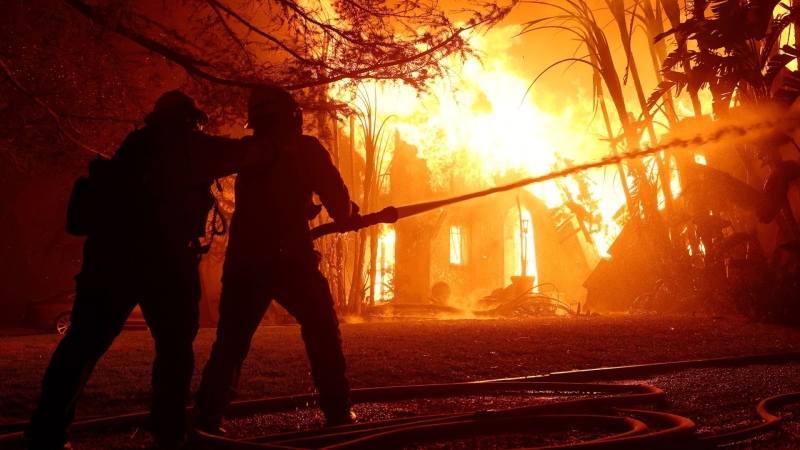 Los Angeles County firefighters spray water on a burning home as the Eaton Fire moved through the area on January 8 in Altadena, California. (Justin Sullivan/Getty Images via CNN Newsource)