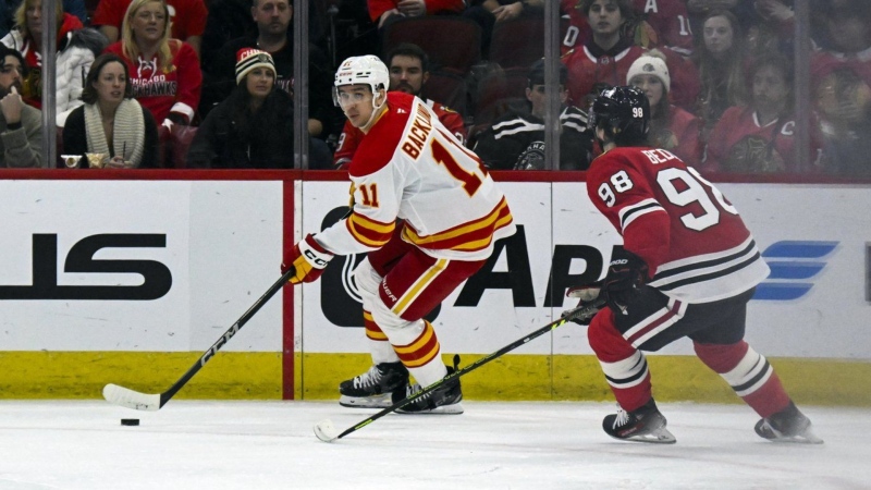 Calgary Flames centre Mikael Backlund moves the puck against Chicago Blackhawks centre Connor Bedard in Chicago on Jan. 13, 2025. (AP Photo/Matt Marton)