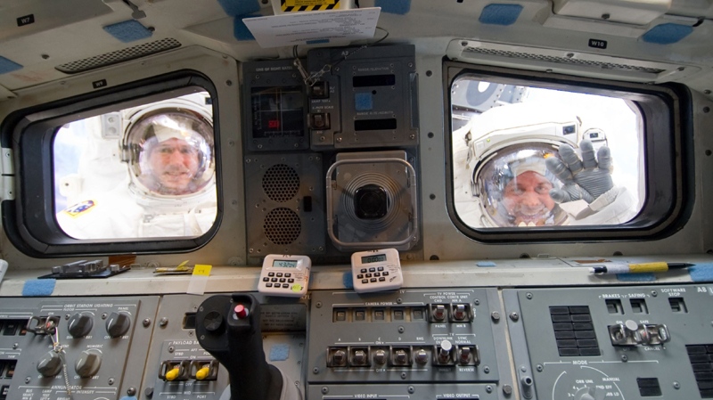 NASA astronauts Michael Good (left) and Garrett Reisman, both STS-132 mission specialists, look through the aft flight deck windows of space shuttle Atlantis in this image provided by NASA during the mission's third and final session of extravehicular activity Friday May 21, 2010 as construction and maintenance continue on the International Space Station. (AP Photo/NASA)