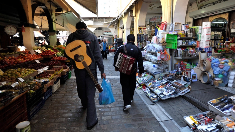 Two street musicians walk in the main vegetable market, in the northern port of city Thessaloniki, Greece, on Thursday, April 12, 2012. (AP / Nikolas Giakoumidis)