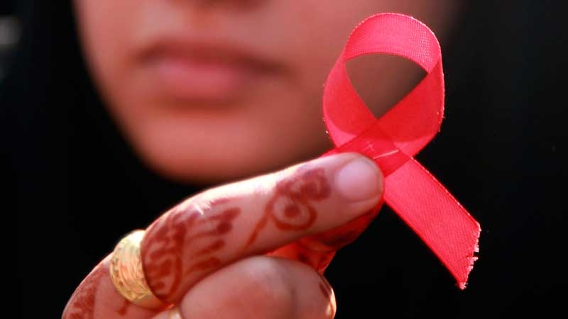 A college student displays a red ribbon, the symbol for AIDS awareness, at a rally to mark World AIDS Day in Jammu, India, Wednesday, Dec. 1, 2010. (AP / Channi Anand)