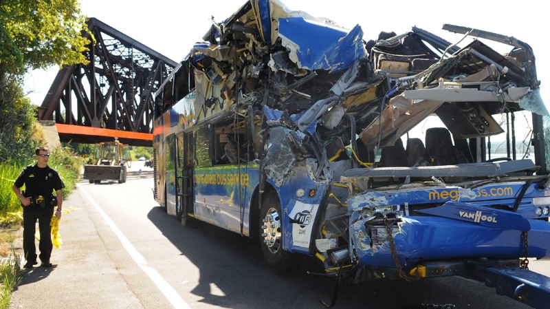 An police officer investigates a fatal bus crash on Onondaga Parkway at the railroad bridge in Syracuse, N.Y., Saturday, Sept. 11, 2010. (The Post-Standard / Peter Chen)